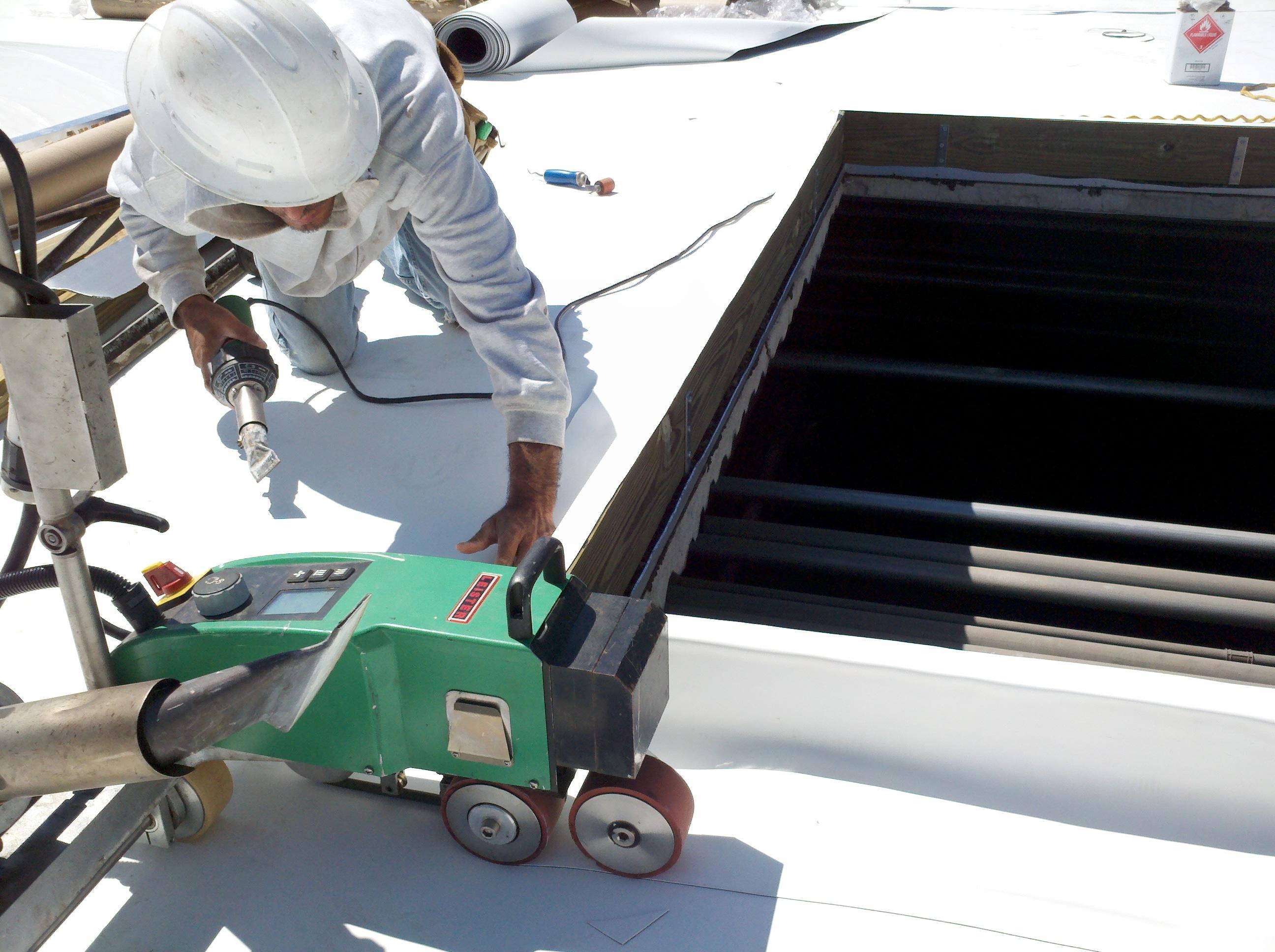 Using a hand-held heat welder on the roofing membrane