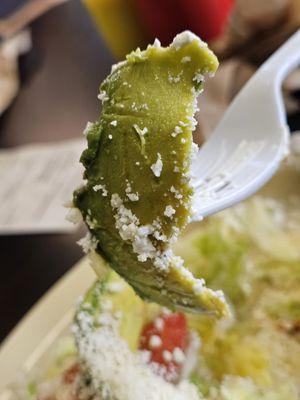 A piece of avocado being held by a fork and getting ready to be eaten and savored.