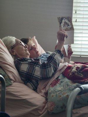 Omi enjoying her new bed with her grandson, looking over pictures from back home.