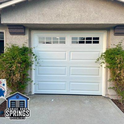 New single-car garage door installation with elegant windows installed, enhancing natural light and aesthetic appeal effortlessly