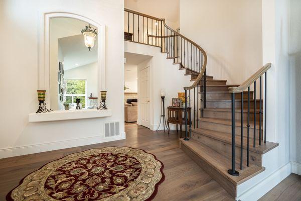 Step into this welcoming entryway with a twisting staircase, window cutout, and gorgeous new flooring.