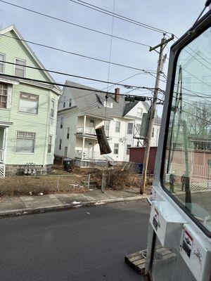 Heavy tree log being safely hoisted over power-lines by our professional certified crane operator!