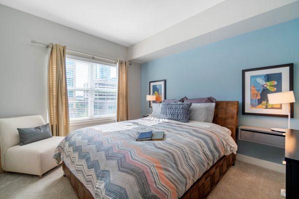 Carpeted and staged bedroom with a large window.