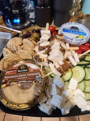 Taste of Greece Hummus Platter  Kalamata olive hummus, tzatziki, chicken skewers, feta cheese cubes, cucumbers, tomatoes, olives,