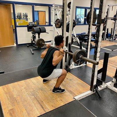 An athlete of the Norfolk Wrestling Academy working on building leg strength through guided weight training with the coaches.