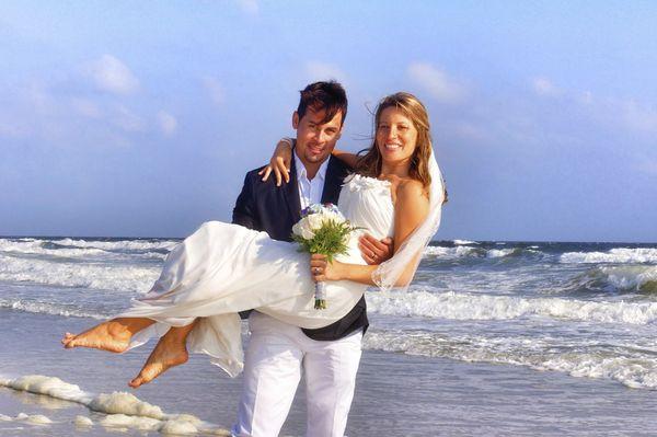 Young Bride in grooms arms on Beach.