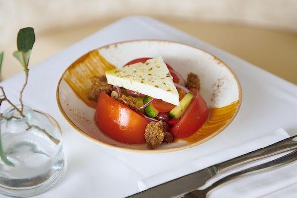 Traditional greek tomato salad served with feta, cucumber, onions, olives and tomato butter