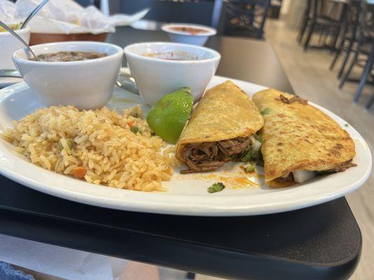 Birria Tacos loaded with cilantro, onions, and lime.  Served with a small consomé.