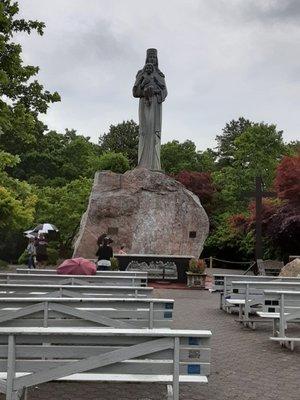 Outdoor Mass area benches and a giant boulder with Our Lady of Long Island