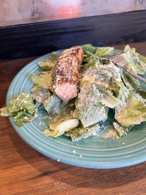 Caesar salad with a small piece of grilled salmon.