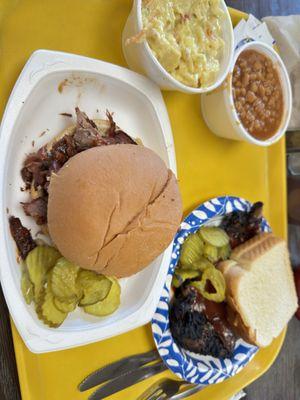 Rib and brisket sandwich with baked beans and potatoe salad sides.