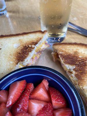 Grilled ham and cheese sandwich with fruit on the side and ginger ale.