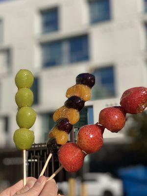 Left to right Green grape Tanghulu, Purple grape and tangerine slices Tanghulu, Strawberry Tanghulu.