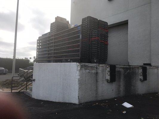 Pallets and boxes stacked high with nothing containing them and keeping them from hitting a car or bystander during high winds.