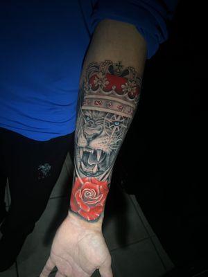 Lion with a crown and rose realism tattoo.