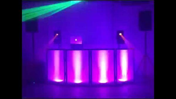 DJ set up QSC speakers. White facade around front of table Par64 led lights that "dance" (move) with the sound of the music playing.