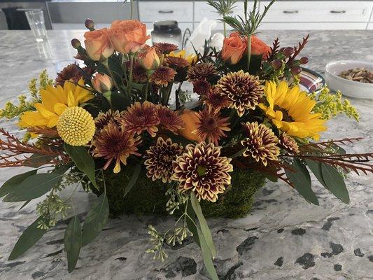 Moss container with fall floral bouquet and small pumpkin.