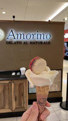 Stracciatella gelato in a small cone with blueberry cheesecake macaron