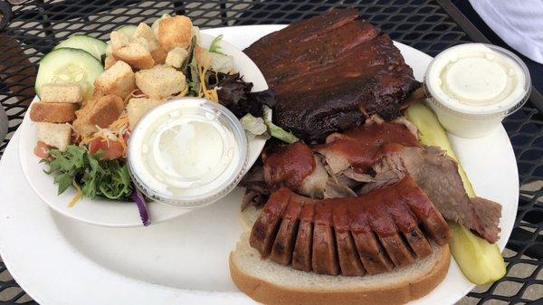 Three way BBQ sampler: ribs, brisket, and sausage with two sides, side salad, plus another side not pictured.