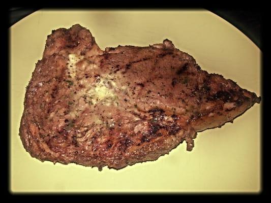 Ribeye steak after being grilled & topped with a pat of garlic herb butter!