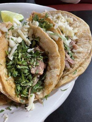 Carnitas tacos with corn tortilla, cilantro and cheese