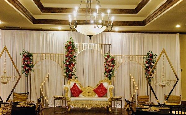 Engagement/ Anniversary setup. Elegant golden frame with flower garland with pink backdrop