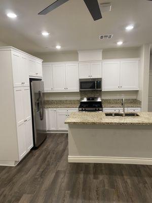 Clean floors, clean island with sink, clean cabinets, and clean kitchen appliances!