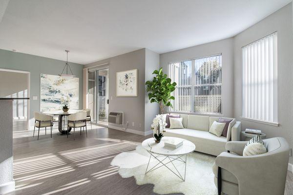 Staged living room featuring large windows, hardwood-style vinyl flooring, and access to a private patio or balcony.