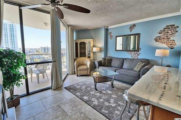 Living room, kitchen bar, balcony with city & beach views.