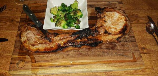 Tomahawk cut pork chop served on a cutting board. Delicious.