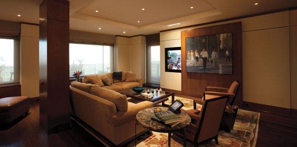 A motorized wallpanel reveals a large television. The surround-sound speaker array is hidden behind acoustical panels.