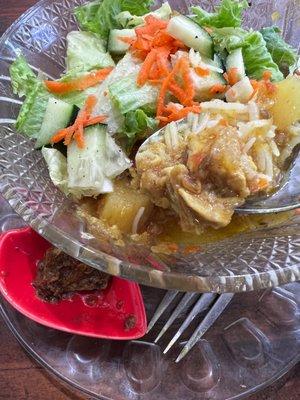 Chicken curry rice bowl with salad on top.