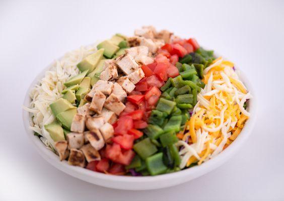 Mexi-Cobb Salad with fajita chicken, green chiles, cheese, avocados and tomatoes on a bed of salad greens.