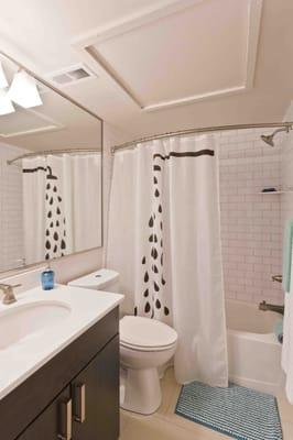 Authentic subway tile bath surrounds, and sleek white quartz counter tops