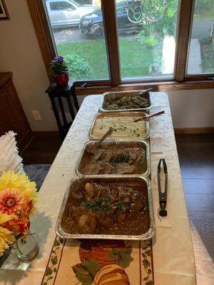 Beef brisket with gravy, sliced roasted pork with gravy, mashed potatoes and green beans with bacon.