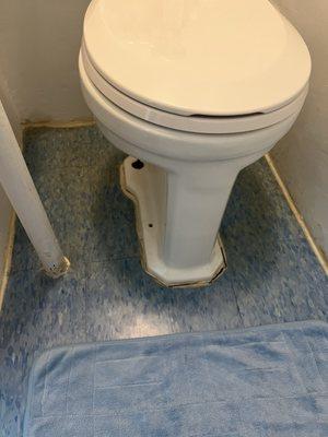 World's most disgusting toilet with cracked caulking and a pipe next to it making it difficult to sit.