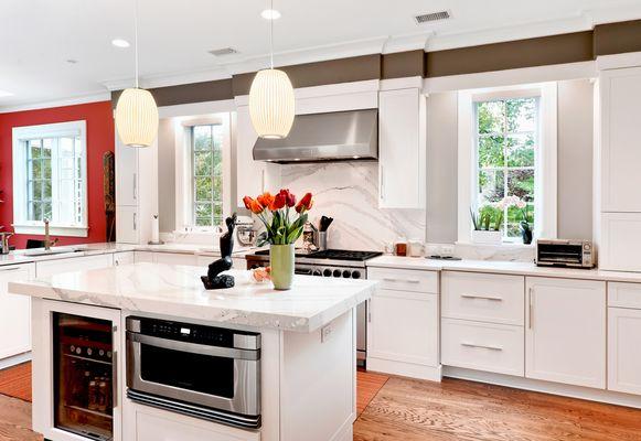 White shaker doors and stainless steel appliances highlight the grey veins on the white stone of this kitchen's backsplash and countertops.