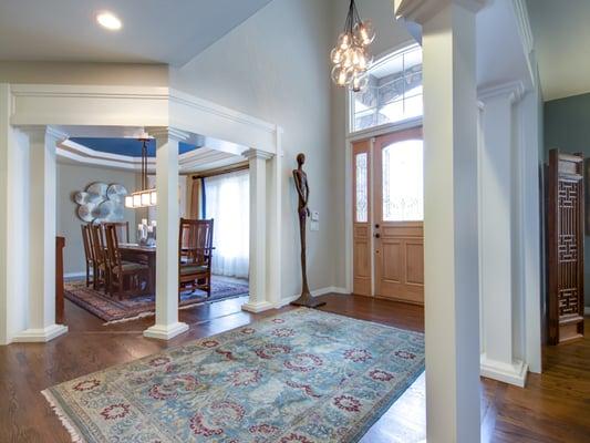 Foyer remodel with custom wood trim & columns, sculpture, and lighting.