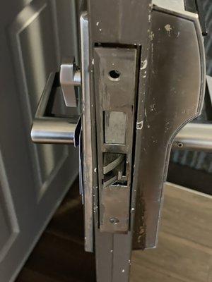 Door latch missing screw and loose making door unsecured.