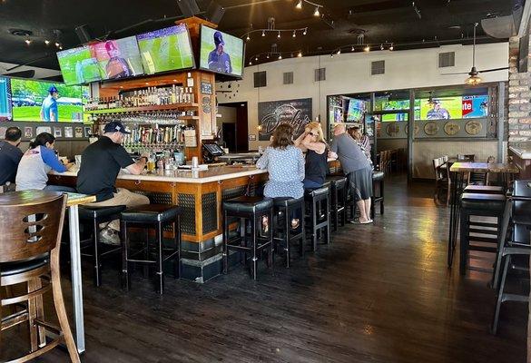 The bar is in the center of the restaurant seating all around the bar, lots of TV's