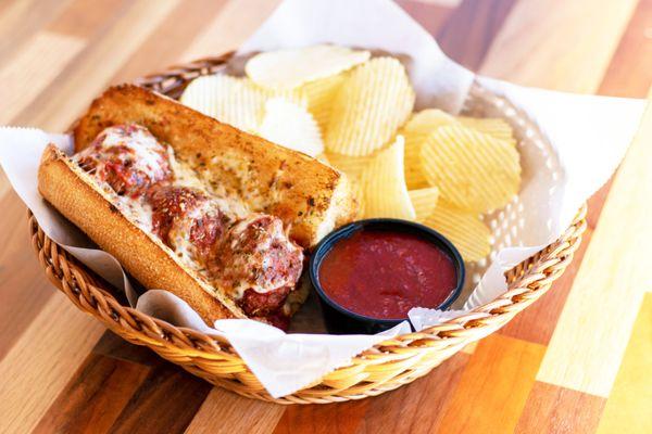 A 6" meatball sub with chips and a side of marinara.