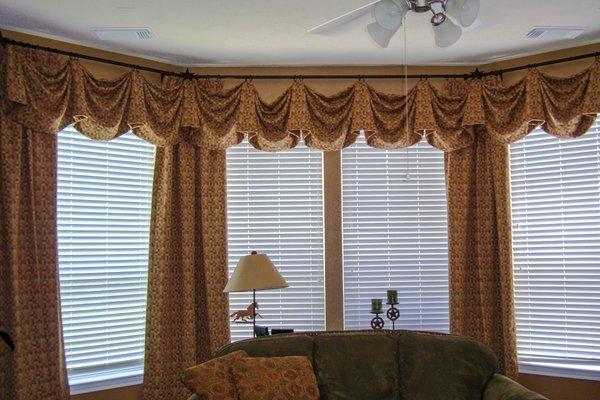 Lovely Empire valance suspended from ab iron rod that exactly matches the bay window angles. The corners are softened with matching drapes.