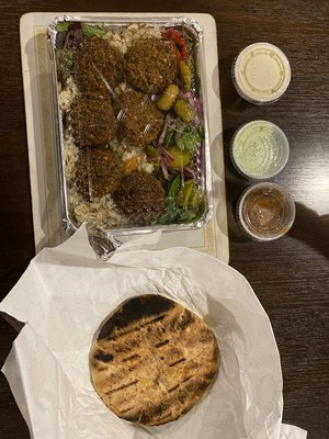 falafel platter with tahini, green sauce, red/orange sauce, and a pita bread.