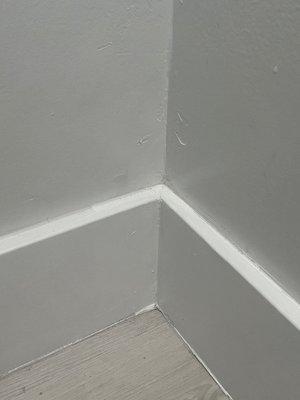 Wrong color paint used on base to cover over poor paint job. They did not use the same color paint on the baseboards as they did on walls!