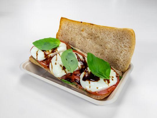 Baked Caprese Sandwich Layered with Fresh Basil Leaves, Tomatoes, Fresh Mozzarella and Balsamic Glaze on Toasted Noble Ciabatta Bread.