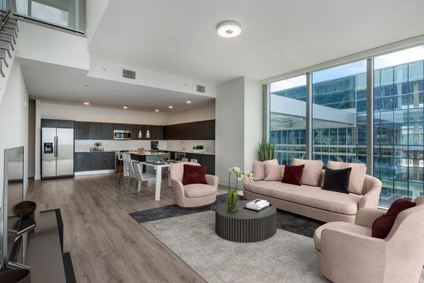 Spacious living room with floor to ceiling windows for ample natural light and wood plank style flooring at Lantower River Landing.