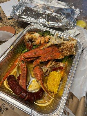 Crab legs, lobster tail, sausage, corn, and broccoli.