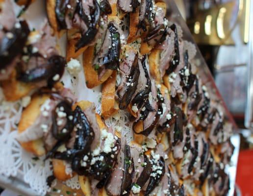 Tenderloin Crostini--garlic toast rounds topped with beef tenderloin, caramelized shallot balsamic reduction, and gorgonzola