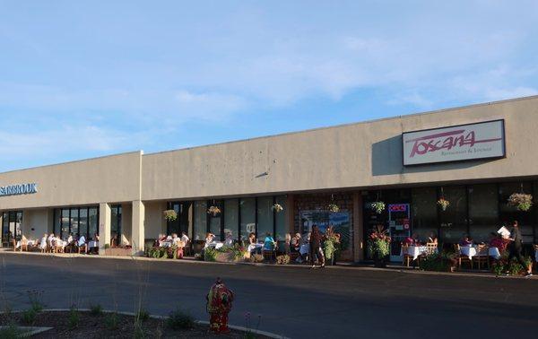 Strip mall storefront, with a lot of patio tables in use at the moment.