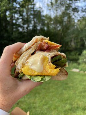 Bacon, egg and cheddar cheese w/ spinach and tomato on an English muffin